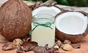 Słoik z olejem kokosowym, otoczony łupinami i połówkami kokosa. Wiele możliwości zastosowanie tego naturalnego produktu.