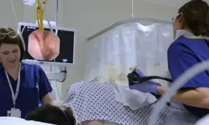 Lekarze przygotowują pacjenta do kolonoskopii, monitorując obraz z endoskopu na ekranie.