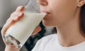 Kobieta pije mleko, które pomaga na zgagę.
