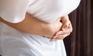 Osoba trzyma się za brzuch, odczuwając ostry ból w lewym boku.