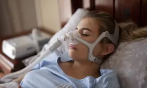 Kobieta śpi z maską CPAP, która pomaga w leczeniu bezdechu sennego. To jedno z domowych sposobów na spokojny sen.