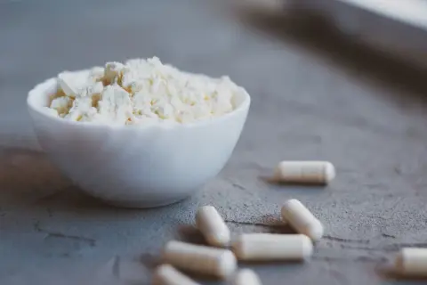 Biały proszek w miseczce i kapsułki. Colostrum na co? Na wsparcie odporności i regeneracji.
