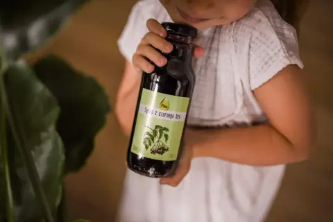 Dziecko trzyma butelkę syropu z czarnego bzu, który jest naturalnym wsparciem dla odporności.