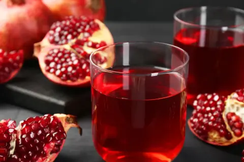 Szklanki z rubinowym sokiem z granatu i świeże owoce. Odkryj sok z granatu właściwości i ciesz się jego smakiem.