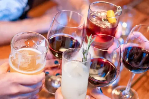 Ludzie wznoszą toasty różnymi napojami. Pamiętaj, że woda to najlepsze, co wypłukuje alkohol z organizmu.