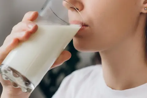 Kobieta pije mleko, które pomaga na zgagę.