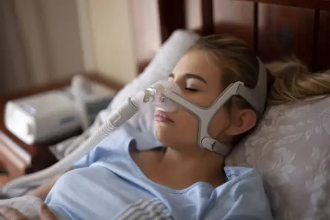 Kobieta śpi z maską CPAP, która pomaga w leczeniu bezdechu sennego. To jedno z domowych sposobów na spokojny sen.