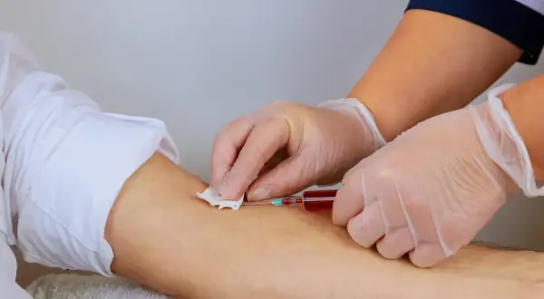 Pielęgniarka pobiera krew do strzykawki. Warto zadbać o odpowiedni poziom hemoglobiny przed oddaniem krwi, by pomóc innym.