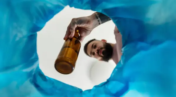 Mężczyzna wyrzuca butelkę, symbolizując początek regeneracji organizmu po odstawieniu alkoholu.