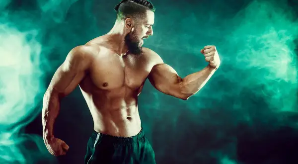Mięśniowy mężczyzna napina biceps. Czy to efekt kwasu mlekowego?