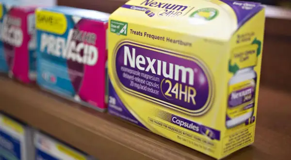 Leki na refluks bez recepty: pudełka Nexium 24HR i Prevacid 24HR na półce aptecznej.