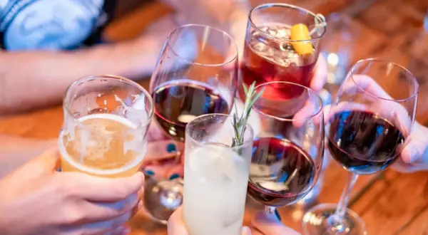 Ludzie wznoszą toasty różnymi napojami. Pamiętaj, że woda to najlepsze, co wypłukuje alkohol z organizmu.
