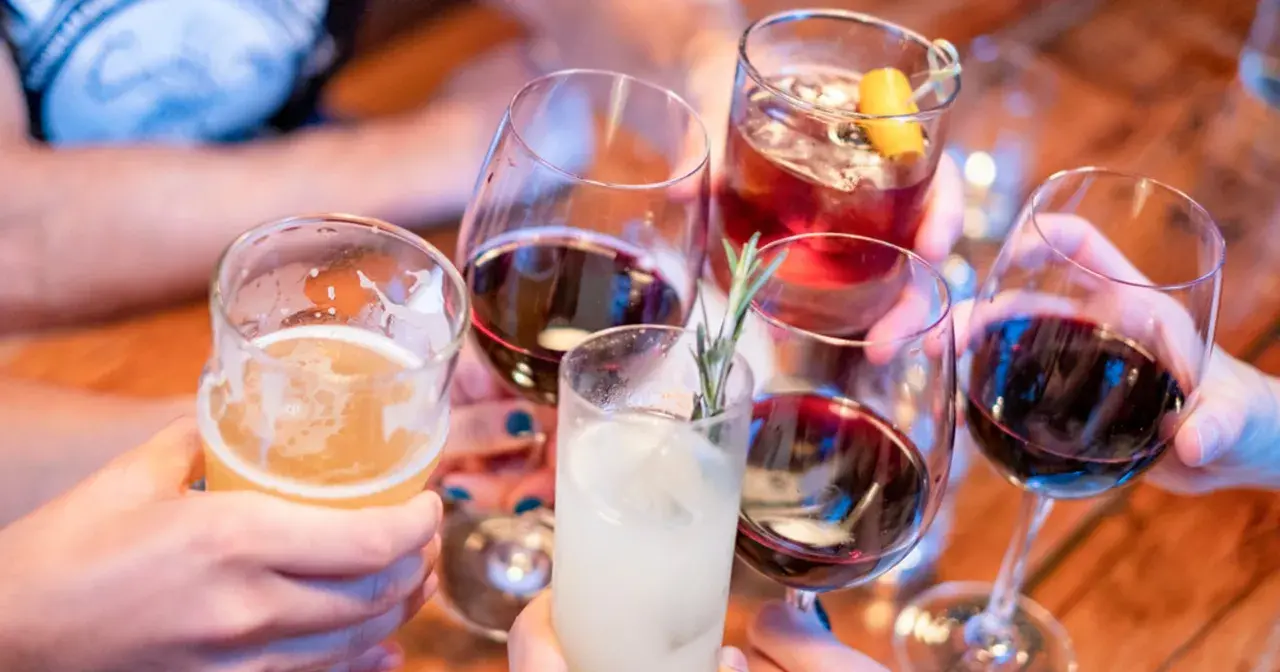 Ludzie wznoszą toasty różnymi napojami. Pamiętaj, że woda to najlepsze, co wypłukuje alkohol z organizmu.