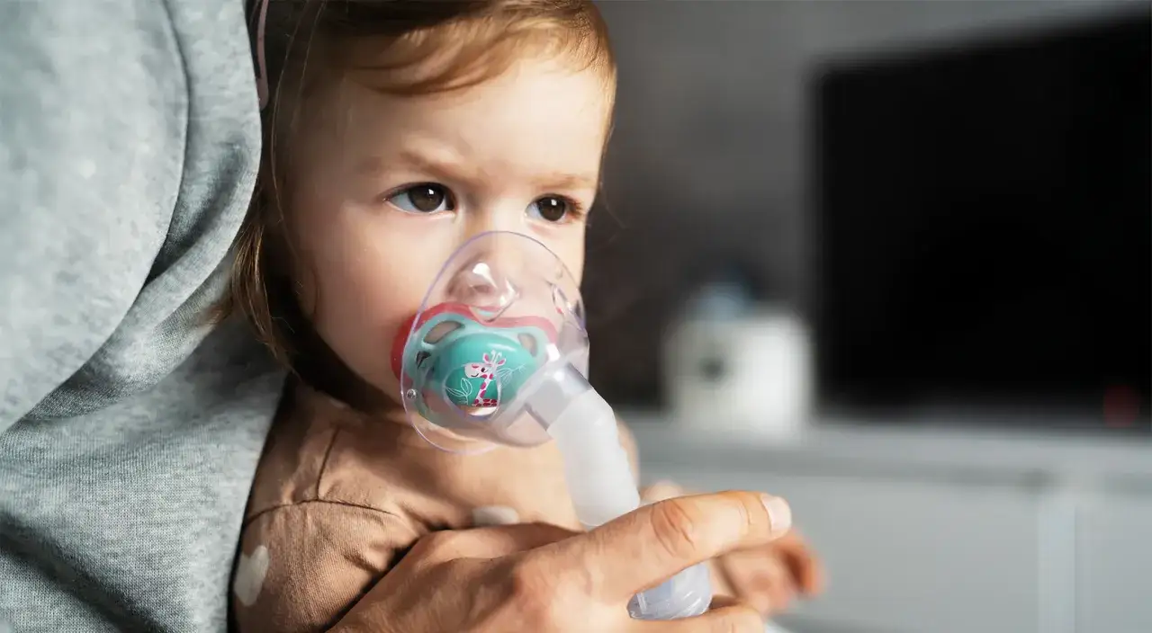 Małe dziecko z maską inhalacyjną na twarzy, wdychające parę z soli fizjologicznej.