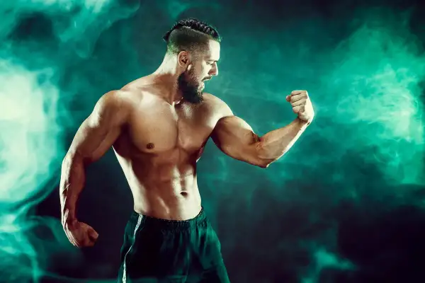 Mięśniowy mężczyzna napina biceps. Czy to efekt kwasu mlekowego?